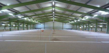 leere Lagerhalle für Lebensmittel und Notfallgüter mit Beleuchtung und grünen Stahlträgern als Deckengerüst