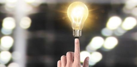 Fotomontage mit einer Hand mit ausgestrecktem Zeigefinger, auf der eine leuchtende Glühlampe steht und ausbalanciert wird